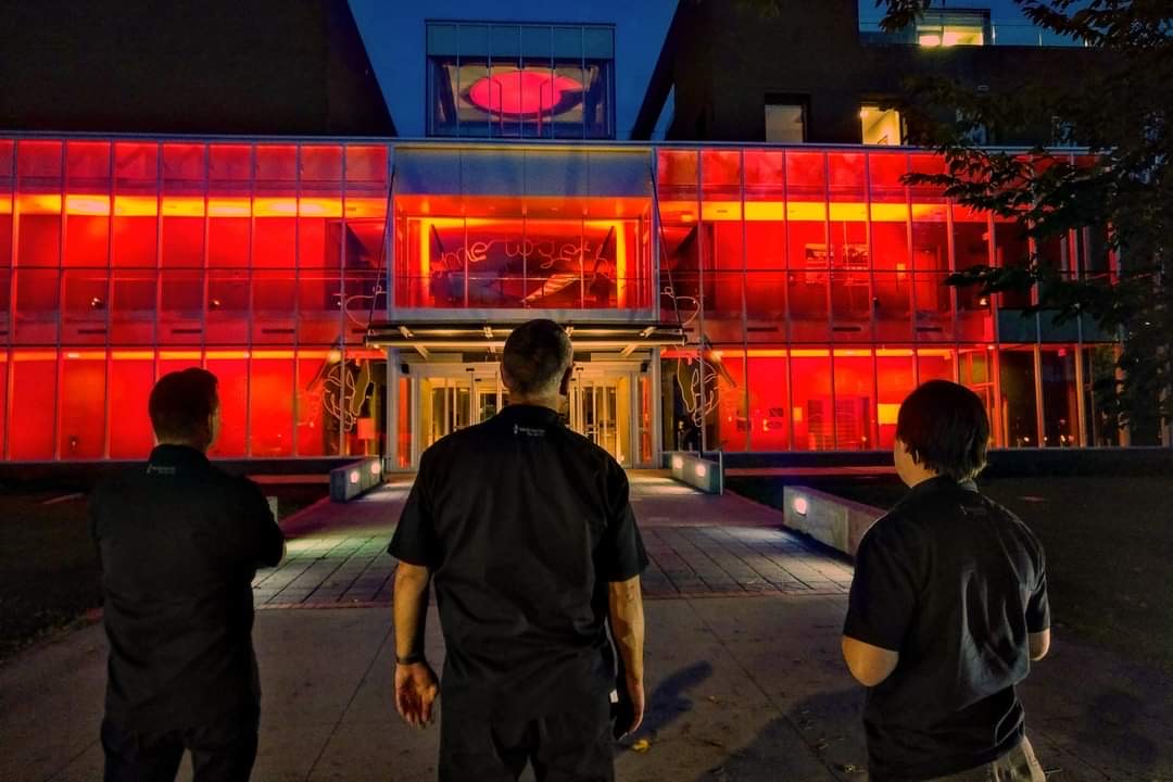 Photo of three technicians looking at the Esplanade Arts & Heritage Centre lit up in red lights