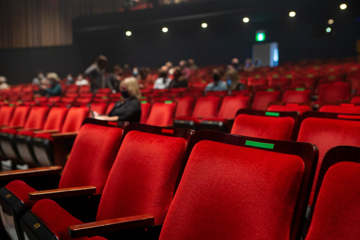 A nearly empty theatre, with seats marked for social distancing