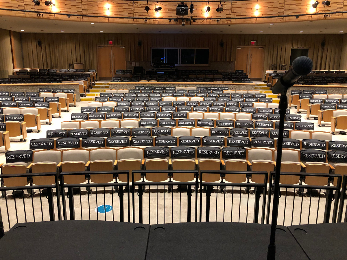 View of the physically-distanced seating plan from the stage. Most seats are marked "reserved" leaving a few safely distanced bubbles.