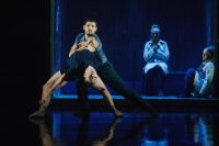 A duo of dancers. The woman leans backward and the man pulls her back.