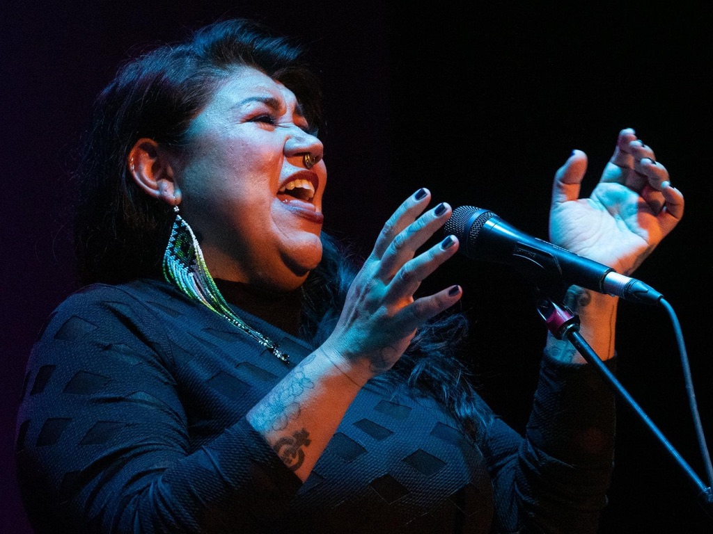 Celeigh Cardinal is singing in front of a microphone.