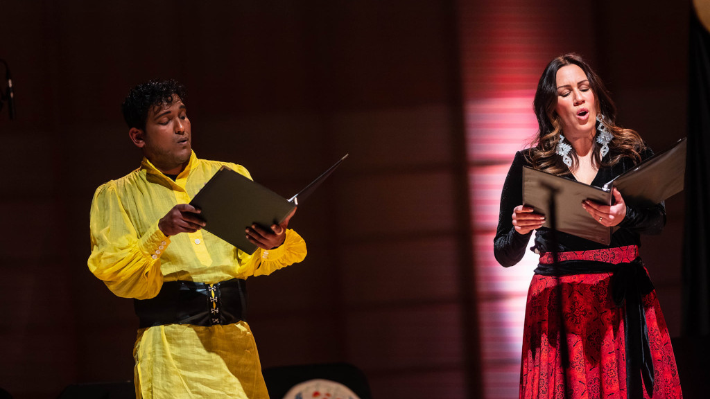 Un homme et une femme portant des vêtements traditionels chantent ensemble.