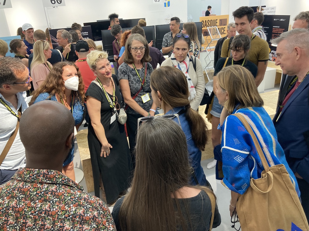 Un groupe de délégués et d'artistes entassés dans un lieu de type marché.