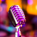 A retro-style microphone is in the centre of the image. The orange and pink-hued background is blurred.