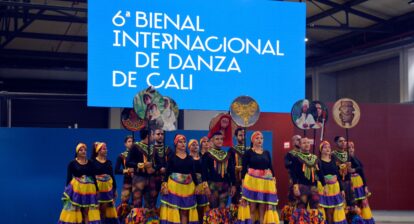 An image of a folklore dance group in Cali, Colombia standing in front of a danner that says "6e Bienal Internacional de Danza de Cali".