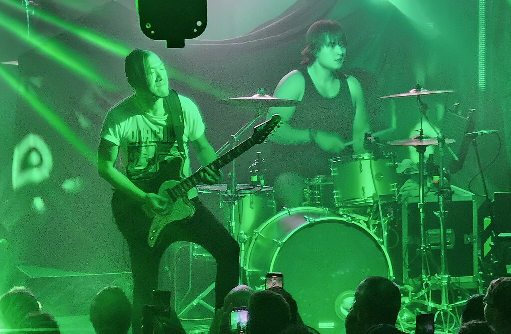 Guitariste et joueur de batterie; les fans enregistrent le concert sur leurs téléphones intelligents.