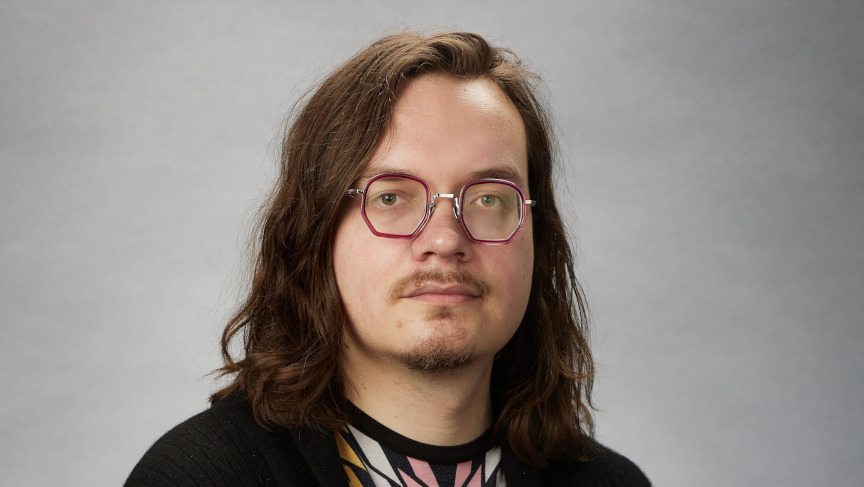 Man with long hair and beard wearing glasses.
