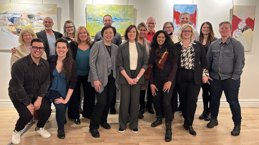 Un groupe de personnes souriant devant des tableaux