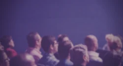 A crowd, presumably for a live performance, looking towards the right of the frame.