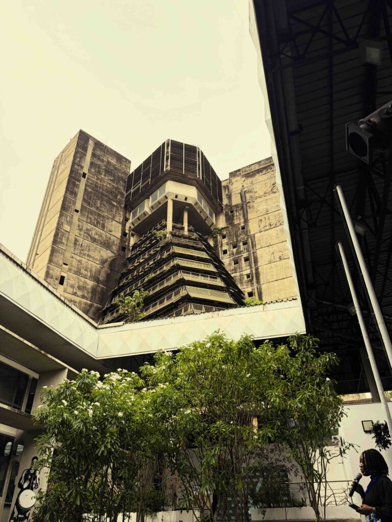 In the commercial heart of Abidjan (Le Plateau district), an MC announces the next MASA event in the courtyard of the Institut Français de Côte d'Ivoire - a key example of post-independence Tropical Brutalism. Raw exposed concrete sunshades and bold geometric volumes were characteristic of 1970s public architecture in West Africa.
