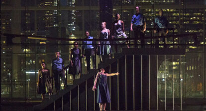 Un groupe de danseurs se tenant debout sur un escalier dans le noir.