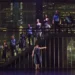 A group of dancers standing on a staircase on a dark stage.