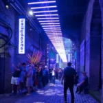 A cobblestone street with people lining up to see a show.