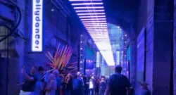 A cobblestone street with people lining up to see a show.