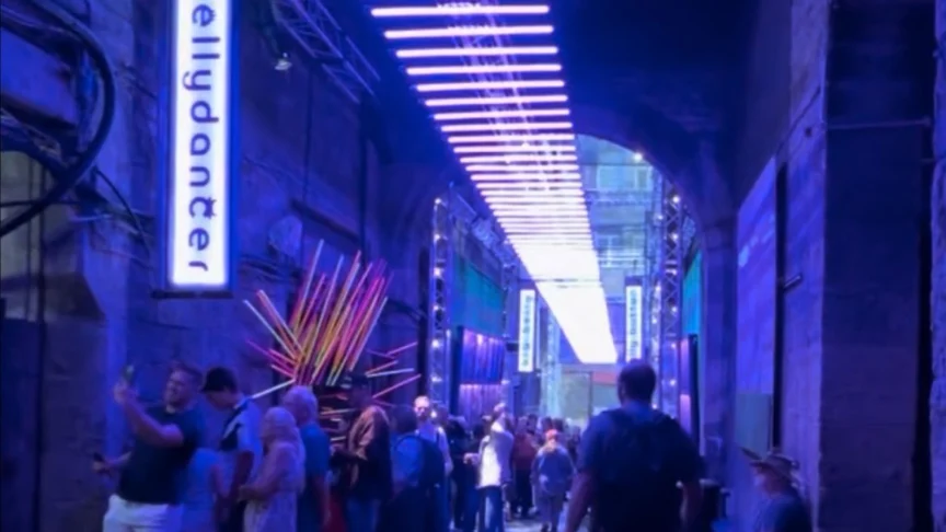 A cobblestone street with people lining up to see a show.
